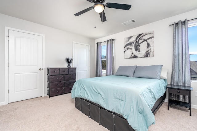 bedroom featuring light carpet, a ceiling fan, visible vents, and baseboards