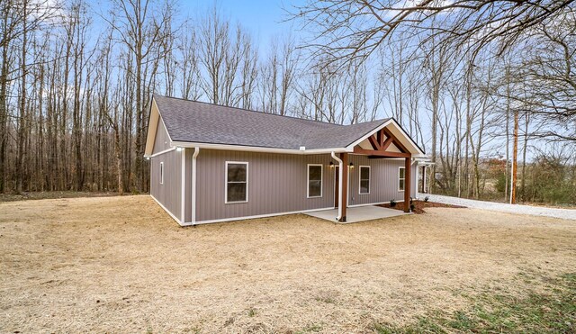 view of front of property featuring a patio and roof with shingles