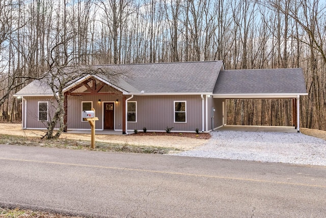 ranch-style house featuring driveway, an attached carport, and roof with shingles