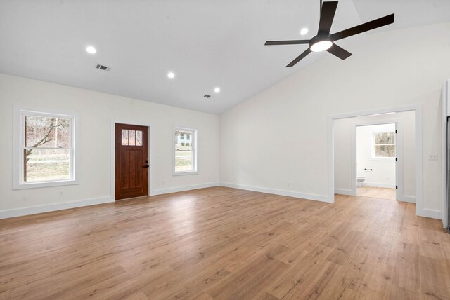 unfurnished living room with light wood-type flooring, a wealth of natural light, visible vents, and baseboards