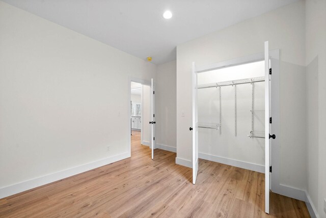 unfurnished bedroom with recessed lighting, a closet, baseboards, and light wood finished floors