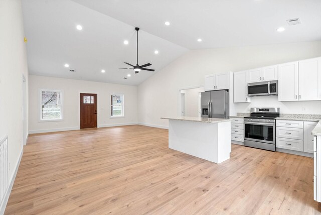 kitchen featuring open floor plan, a center island, stainless steel appliances, light wood-type flooring, and white cabinetry