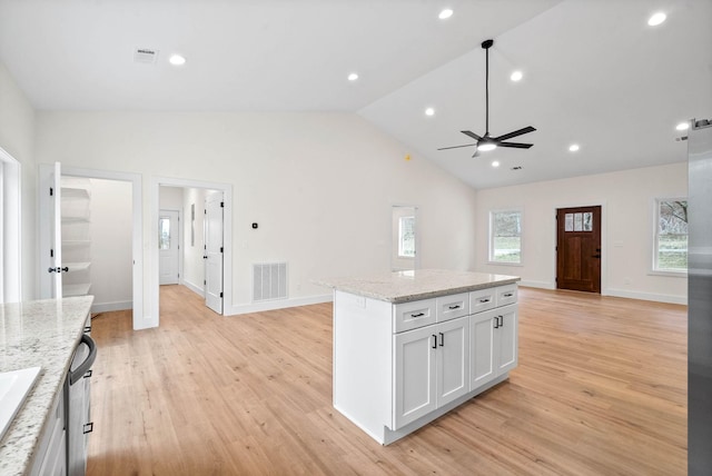 kitchen with open floor plan, white cabinetry, a kitchen island, and visible vents