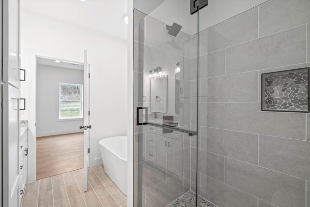 full bathroom featuring a freestanding tub, wood finish floors, a shower stall, and vanity