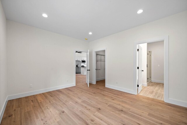 unfurnished bedroom featuring light wood-style floors, recessed lighting, and stainless steel fridge with ice dispenser