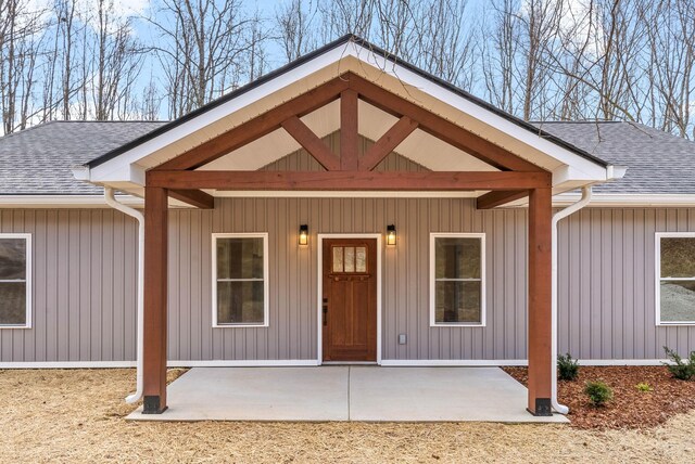 doorway to property featuring a patio and a shingled roof