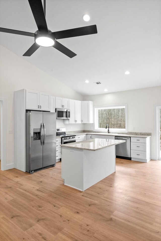 kitchen featuring white cabinets, light stone countertops, light wood-type flooring, and stainless steel appliances