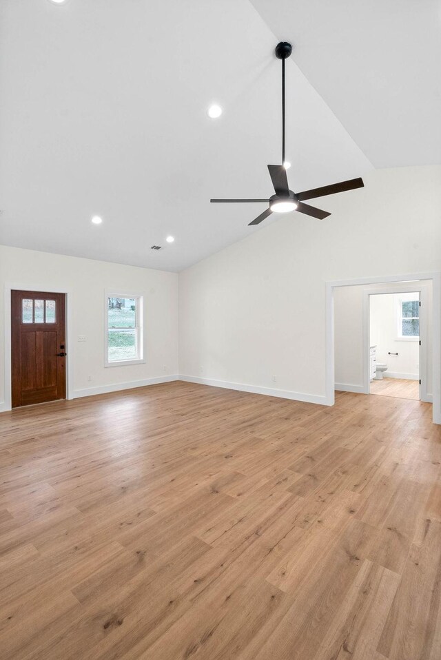 unfurnished living room with light wood-type flooring, vaulted ceiling, baseboards, and ceiling fan