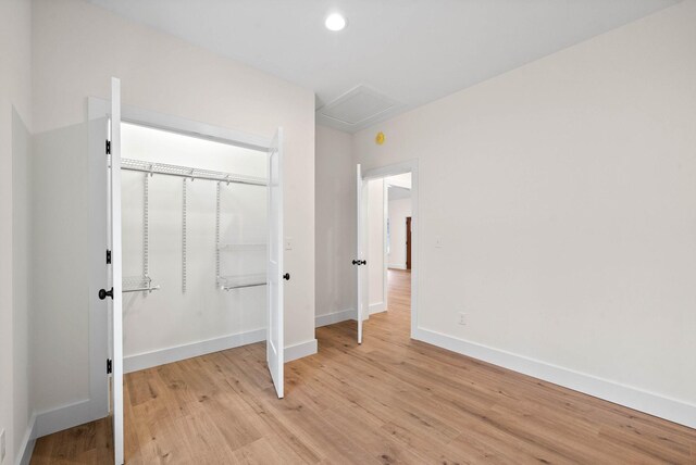 unfurnished bedroom featuring recessed lighting, a closet, attic access, light wood-type flooring, and baseboards