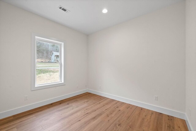 unfurnished room featuring light wood-style floors, visible vents, and baseboards