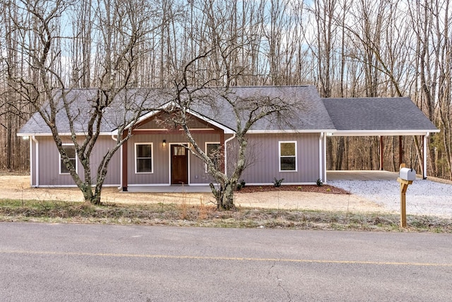 ranch-style home featuring a carport and roof with shingles