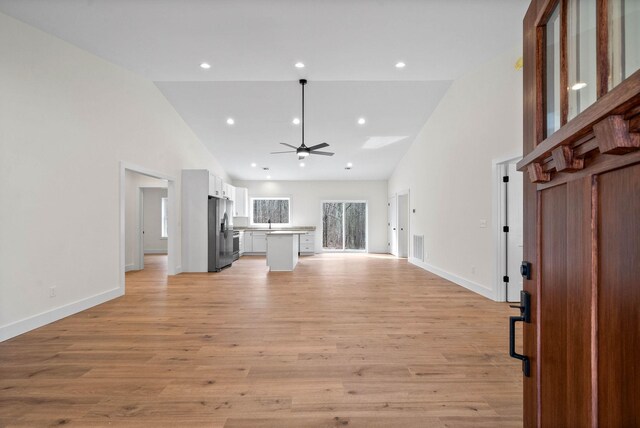 unfurnished living room with a ceiling fan, light wood-style floors, and high vaulted ceiling