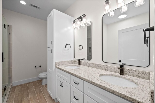 full bath with toilet, double vanity, visible vents, and a sink