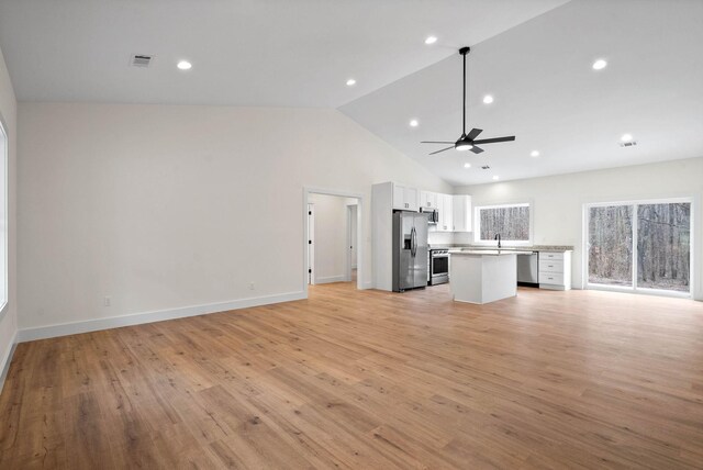 kitchen with open floor plan, stainless steel appliances, light countertops, light wood-type flooring, and white cabinetry