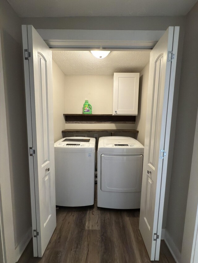 washroom with dark wood-type flooring, washing machine and dryer, cabinet space, and a textured ceiling