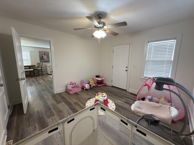 game room featuring dark wood-type flooring, baseboards, and a ceiling fan