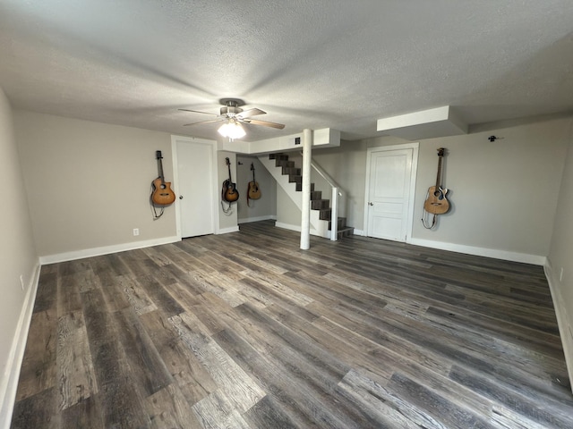 finished basement with stairs, baseboards, dark wood finished floors, and a textured ceiling