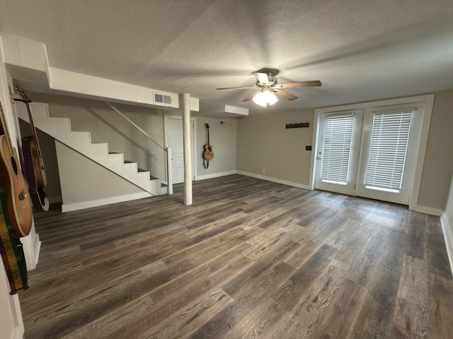 below grade area featuring stairs, baseboards, dark wood finished floors, and a textured ceiling