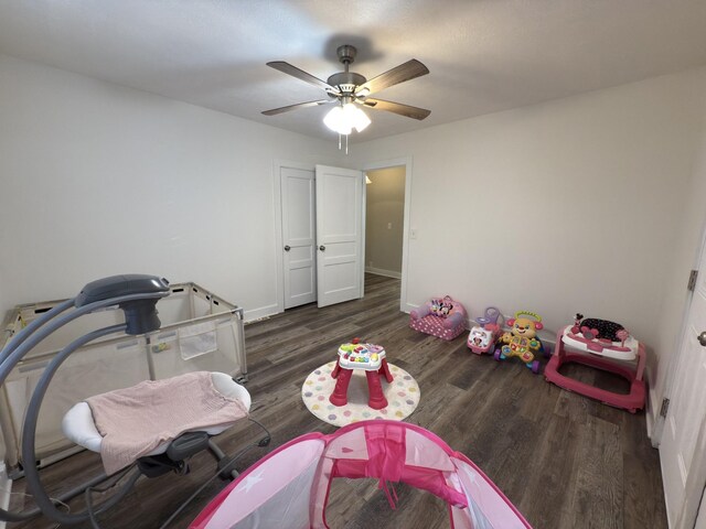 playroom with ceiling fan, dark wood-type flooring, and baseboards