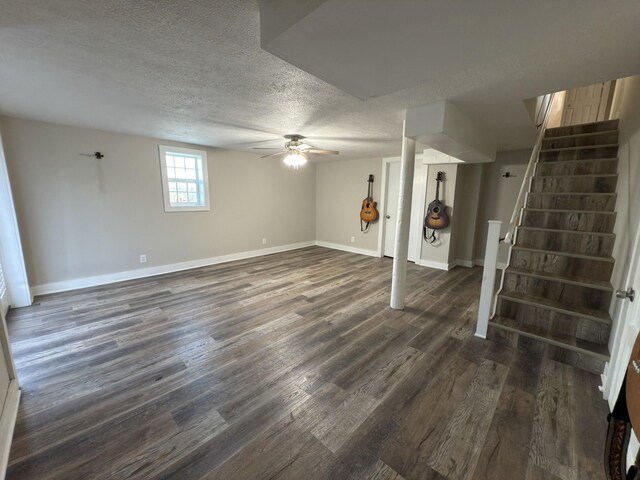 below grade area featuring baseboards, dark wood-style floors, ceiling fan, stairway, and a textured ceiling