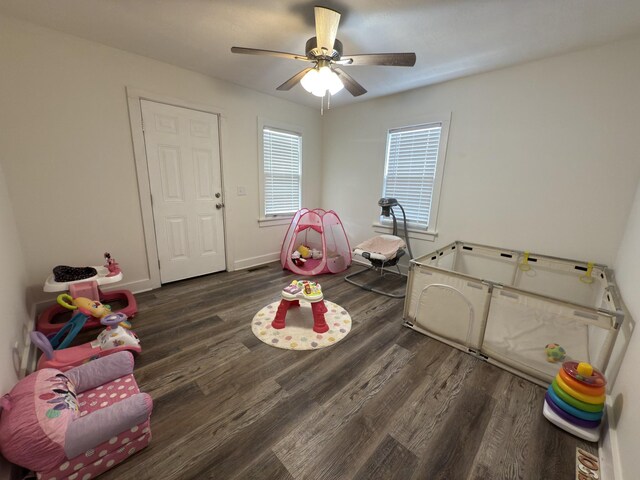 playroom featuring ceiling fan, baseboards, and dark wood finished floors