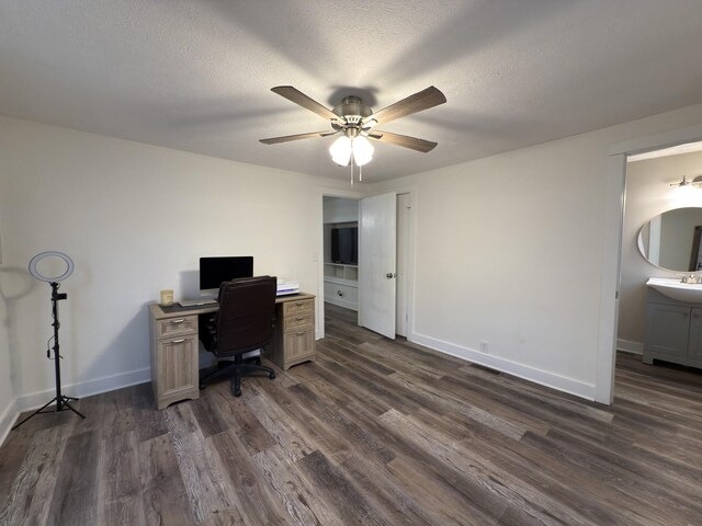 office space with ceiling fan, a textured ceiling, a sink, baseboards, and dark wood-style floors