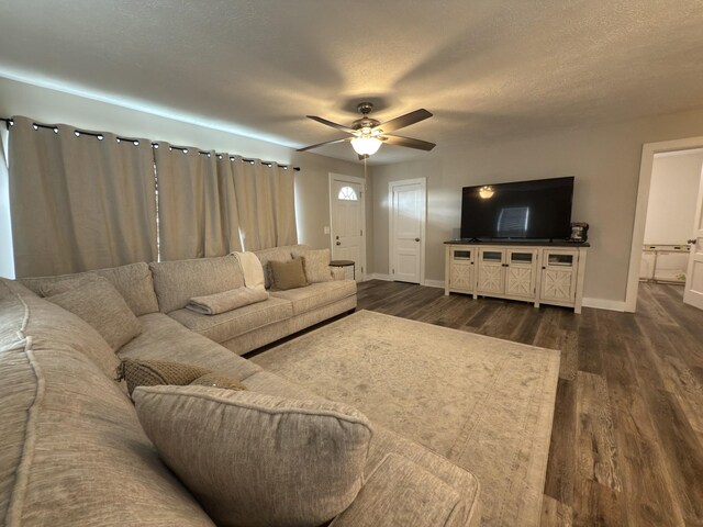 living area with dark wood-type flooring, a textured ceiling, baseboards, and a ceiling fan