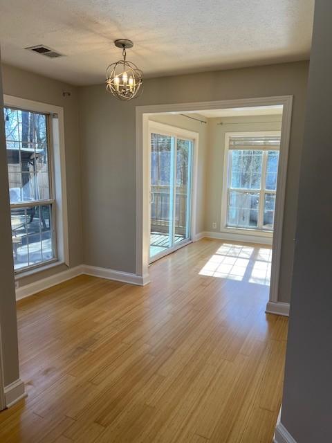 unfurnished dining area with light wood-style floors, plenty of natural light, and visible vents