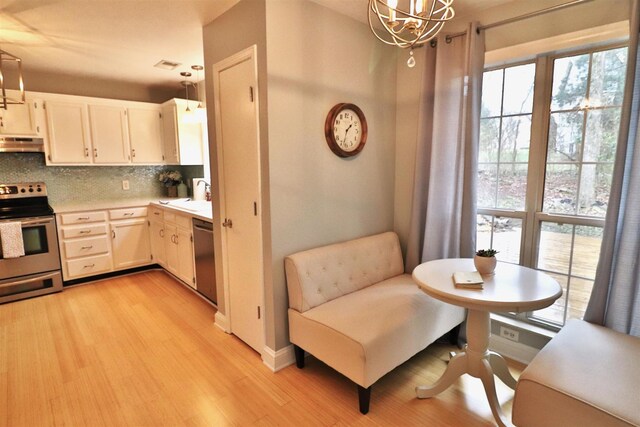 kitchen featuring decorative backsplash, decorative light fixtures, stainless steel appliances, light countertops, and under cabinet range hood