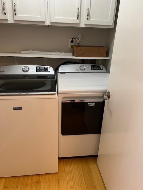 laundry room with cabinet space, light wood finished floors, and separate washer and dryer