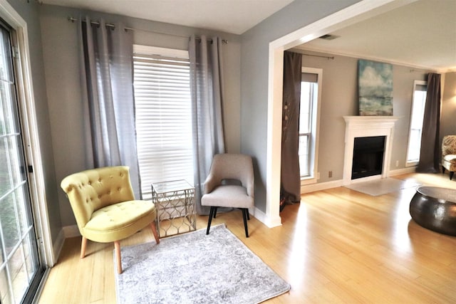 living area with light wood-type flooring, a fireplace, visible vents, and baseboards