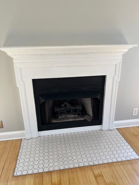 interior details featuring wood finished floors, a fireplace with flush hearth, and baseboards