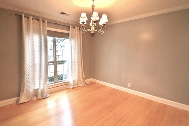 spare room featuring a chandelier, crown molding, baseboards, and wood finished floors