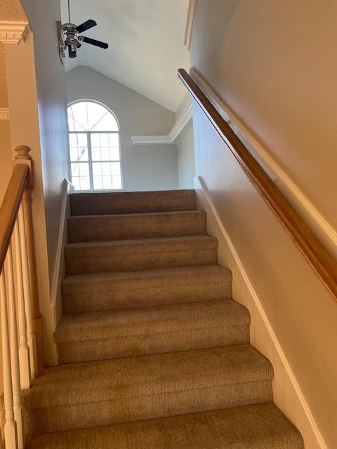 staircase with vaulted ceiling and a ceiling fan