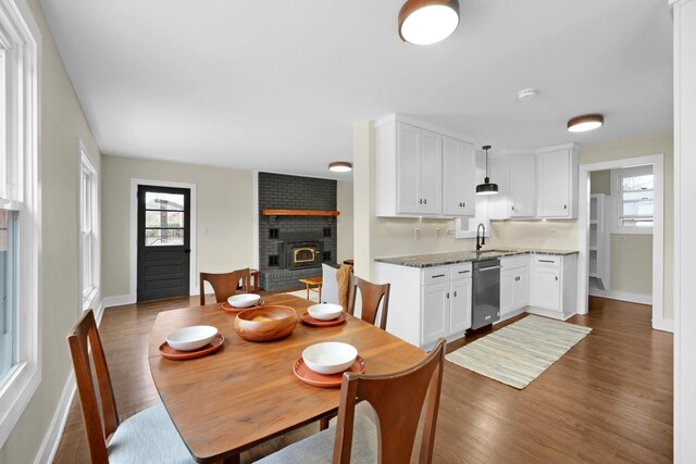 dining room with dark wood-style floors, a fireplace, and baseboards