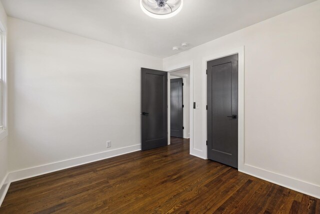 unfurnished bedroom featuring dark wood-style flooring and baseboards