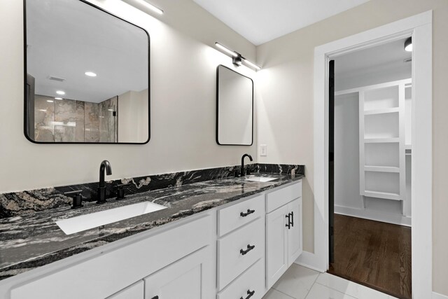 bathroom featuring marble finish floor, double vanity, a sink, and baseboards