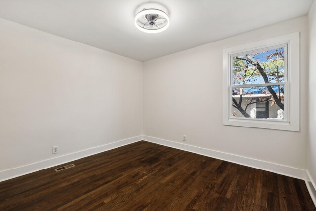 empty room featuring wood finished floors, visible vents, and baseboards