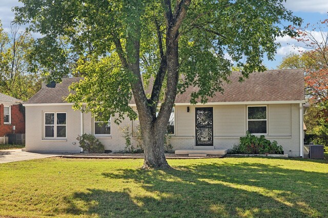 view of front of property with brick siding, a shingled roof, cooling unit, and a front yard