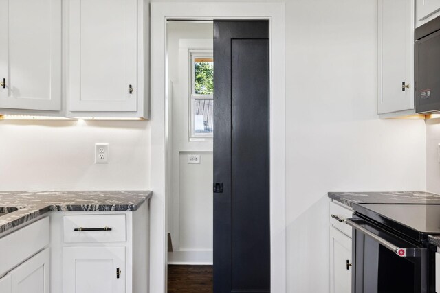 kitchen with electric range oven, white cabinets, and dark stone countertops