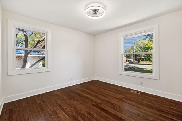 spare room featuring wood finished floors, visible vents, and baseboards