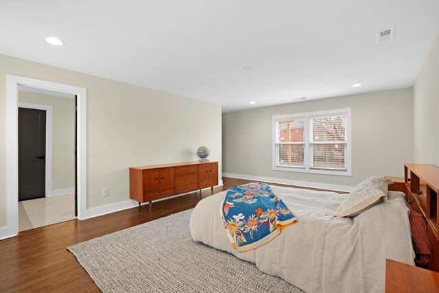 bedroom featuring baseboards, wood finished floors, visible vents, and recessed lighting