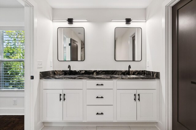 full bathroom with double vanity, a sink, and baseboards