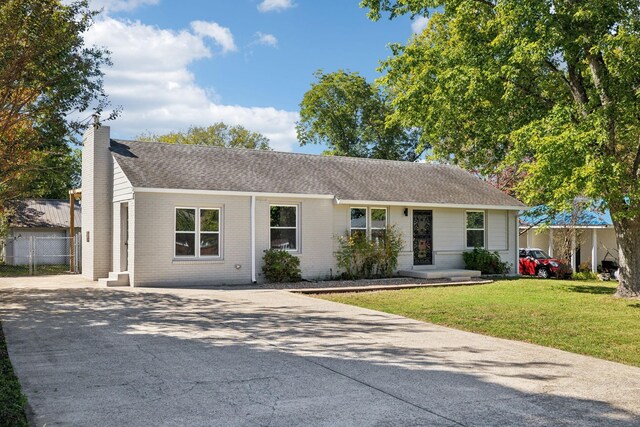 single story home featuring brick siding, driveway, a chimney, and a front lawn