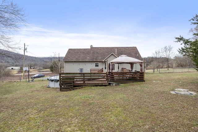 rear view of property featuring a covered pool, a yard, and a gazebo