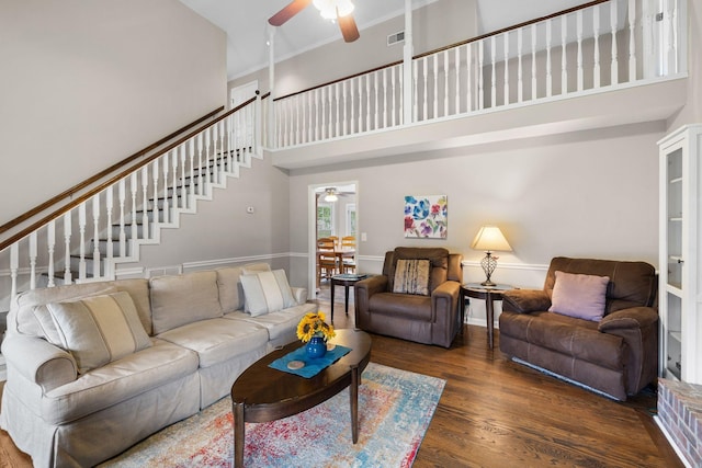 living area featuring ornamental molding, a high ceiling, dark wood finished floors, and a ceiling fan