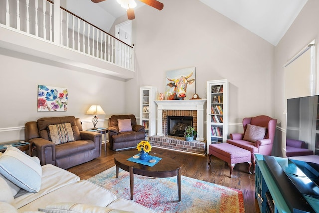 living room featuring ceiling fan, high vaulted ceiling, dark wood-type flooring, and a fireplace