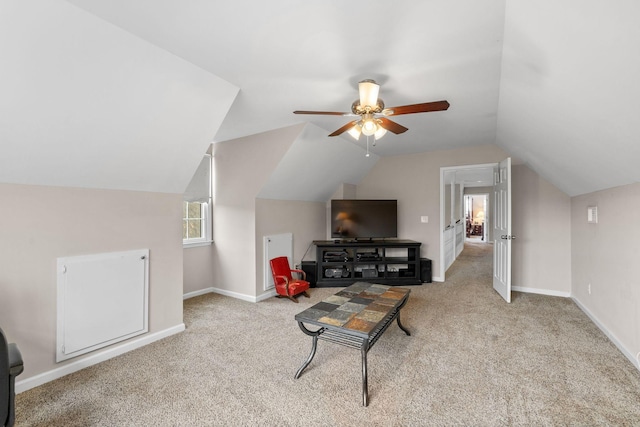 living room featuring baseboards, lofted ceiling, a ceiling fan, and light colored carpet