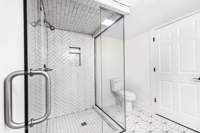 full bathroom featuring baseboards, tiled shower, and toilet