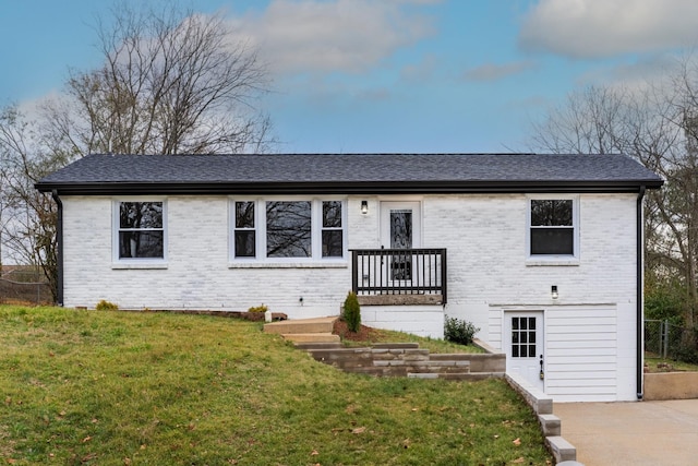 ranch-style home featuring brick siding, roof with shingles, and a front yard